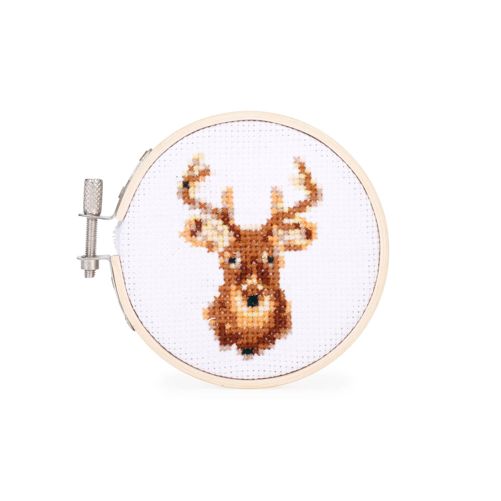 Cross-stitched deer head design in a embroidery hoop on a white background.