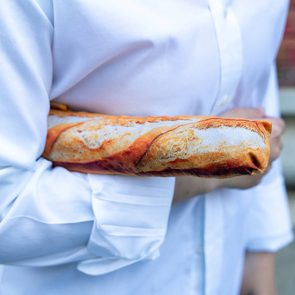 Person holding a baguette umbrella in sleeve, with a blurred white shirt background.