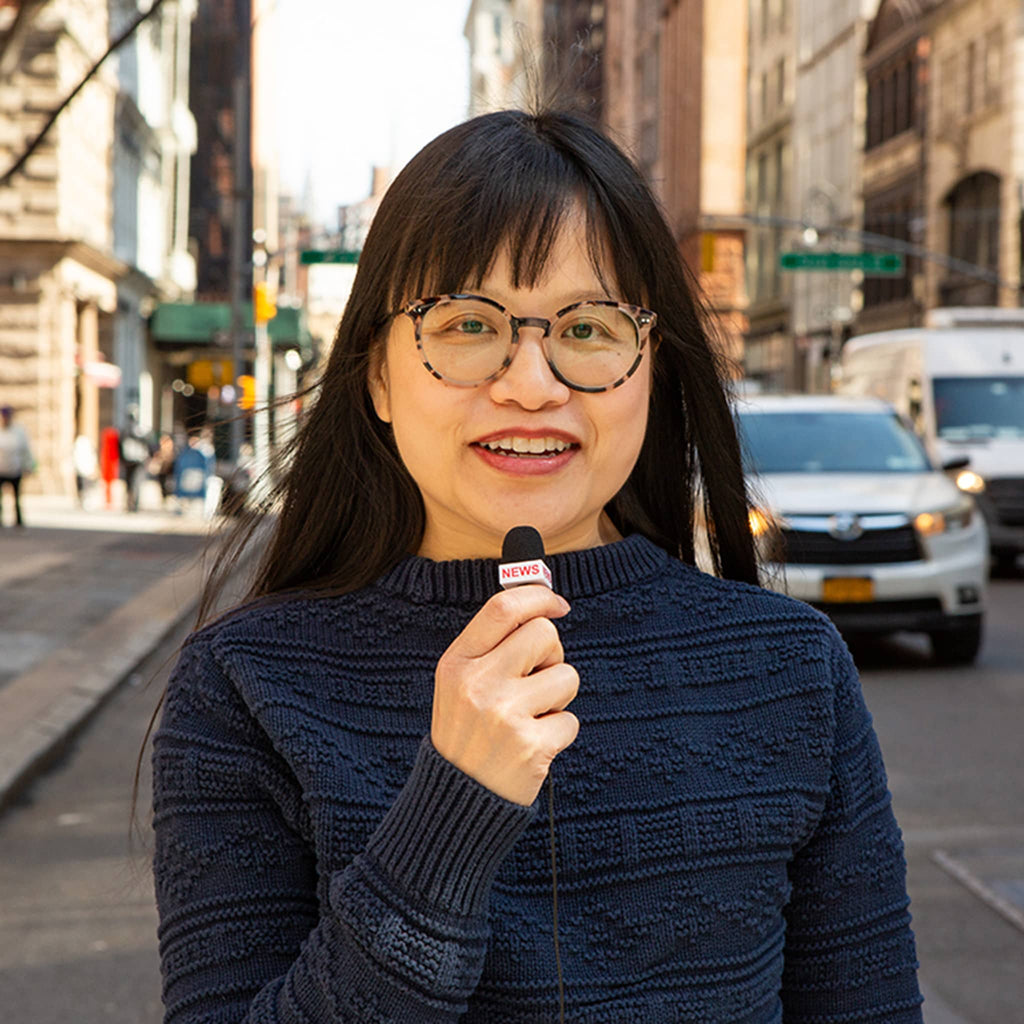 Woman holding a mini microphone on a city street.