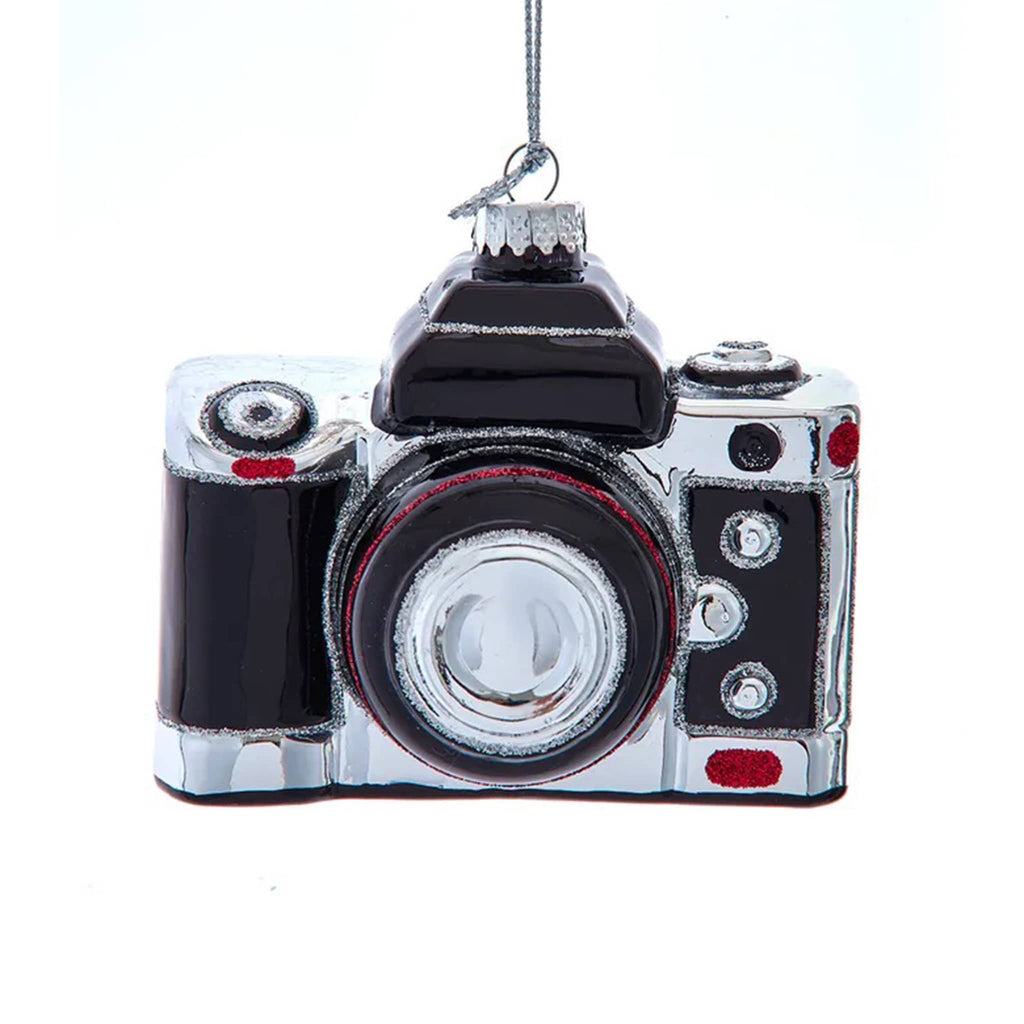 Camera-shaped glass ornament on a white background.