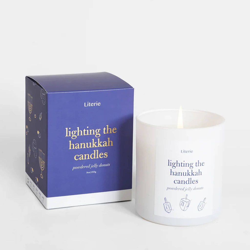 Lit white candle next to a blue box labeled 'Lighting the Hanukkah Candles' on a white background.
