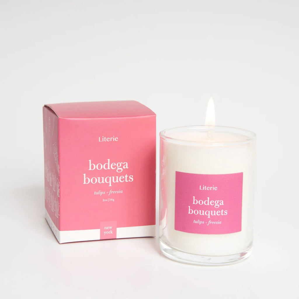 Literie 2 ounce Bodega Bouquets tulips and freesia scented soy and coconut wax blend candle in clear glass votive with pink label and matching pink gift box.