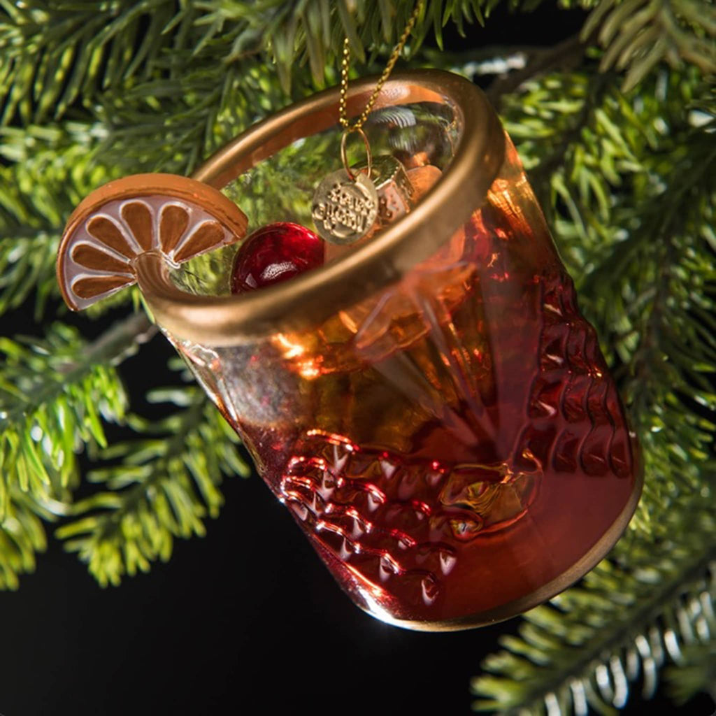 Love and Victory Old-Fashioned hand-blown, hand-painted glass holiday cocktail ornament hanging on an evergreen tree.