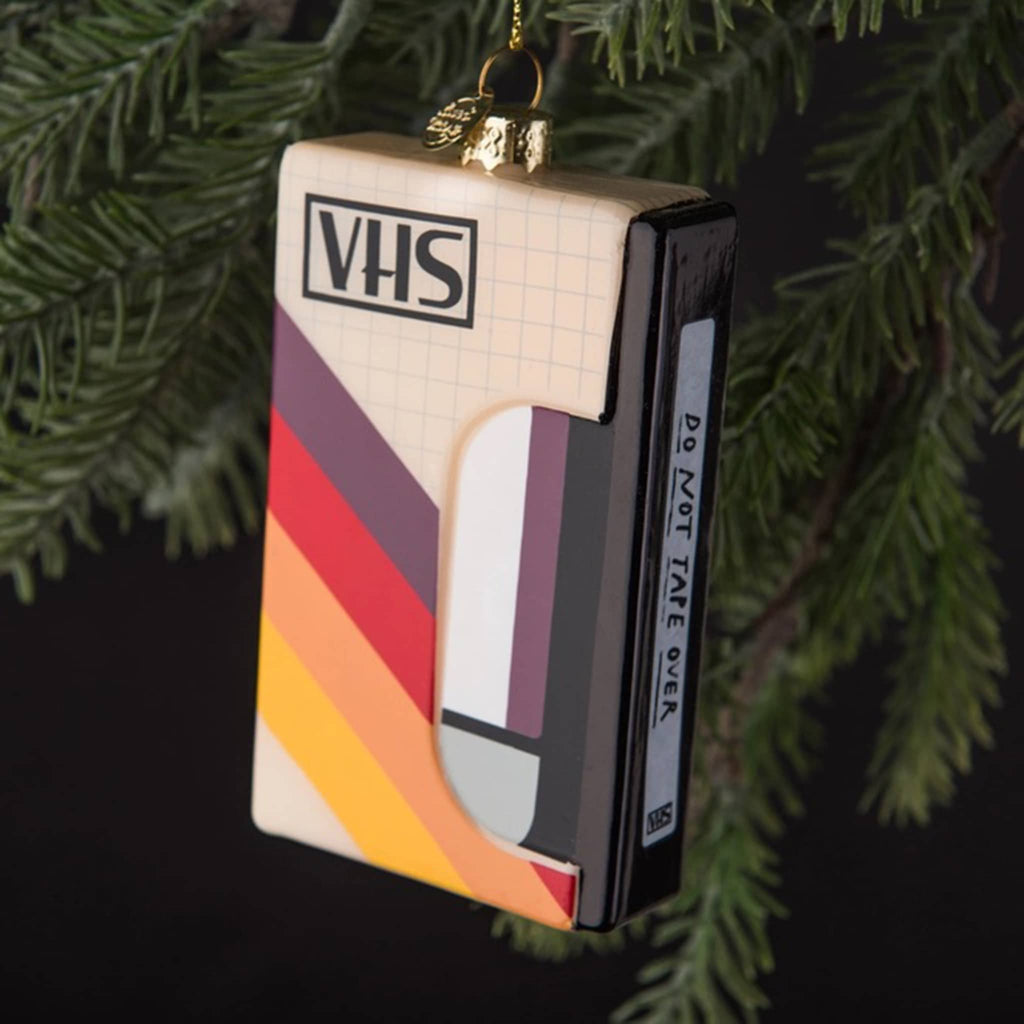 Love and Victory VHS tape hand-blown, hand-painted glass holiday ornament hanging on an evergreen tree.