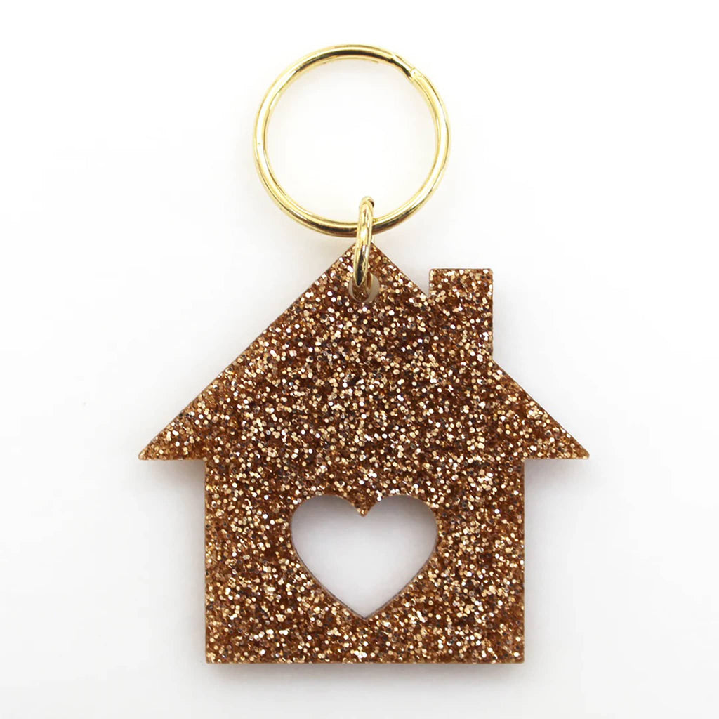 Gold glittery house-shaped keychain with a heart cutout on a white background.