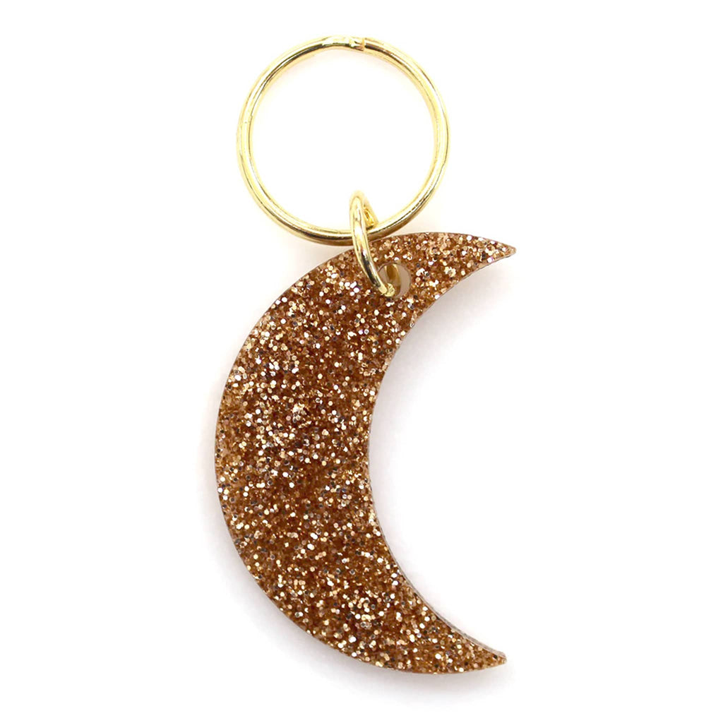 Gold glittery crescent moon keychain on a white background.