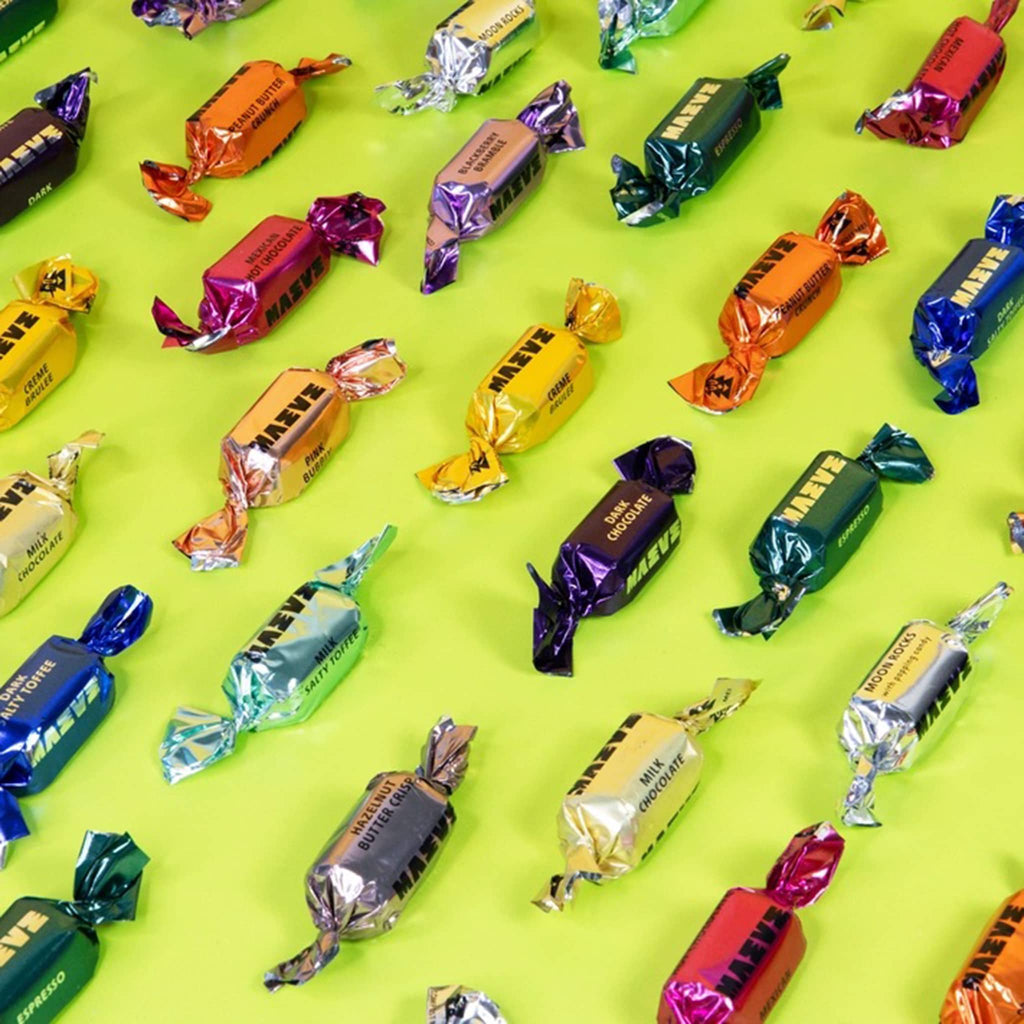 Assorted colorful wrapped chocolate bonbons on a bright green background.