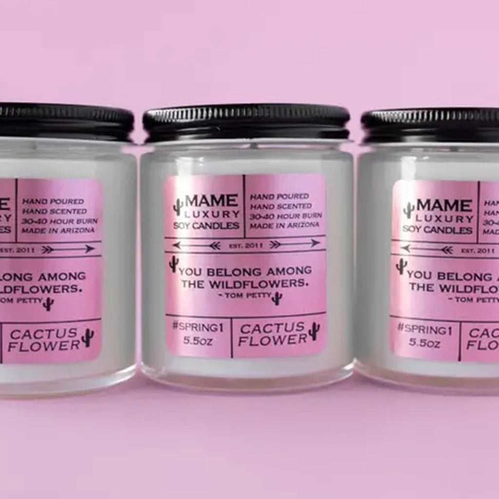MAME Luxury 5.5 ounce soy wax candle, "You belong among the wildflowers" Tom Petty quote candle with a cactus flower scent in a clear glass apothecary jar with black lid and pink label.