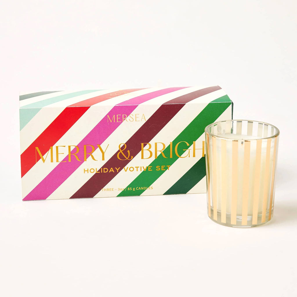 Mer-Sea Good Tidings gold striped holiday votive set with pink, red, green striped box packaging and "merry & bright" in gold foil lettering.