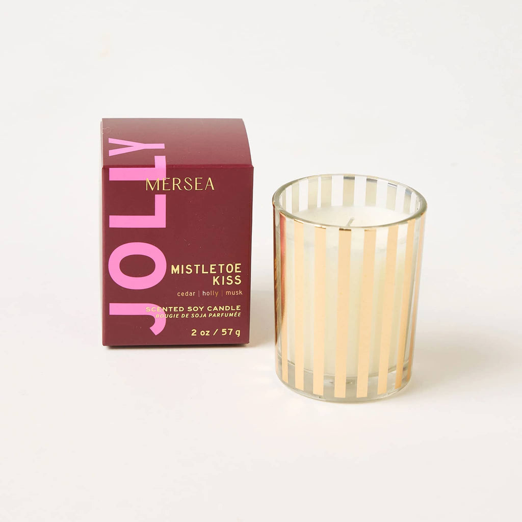 Mer-Sea Good Tidings Mistletoe Kiss scented votive candle in gold striped vessel, beside burgundy box packaging.