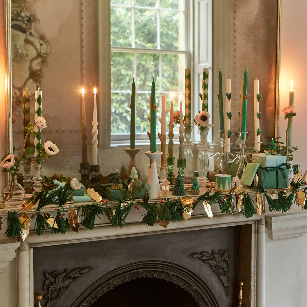 Meri Meri Pine Needles and Golden Holly Christmas holiday paper garland on a mantel with other holiday decorations.