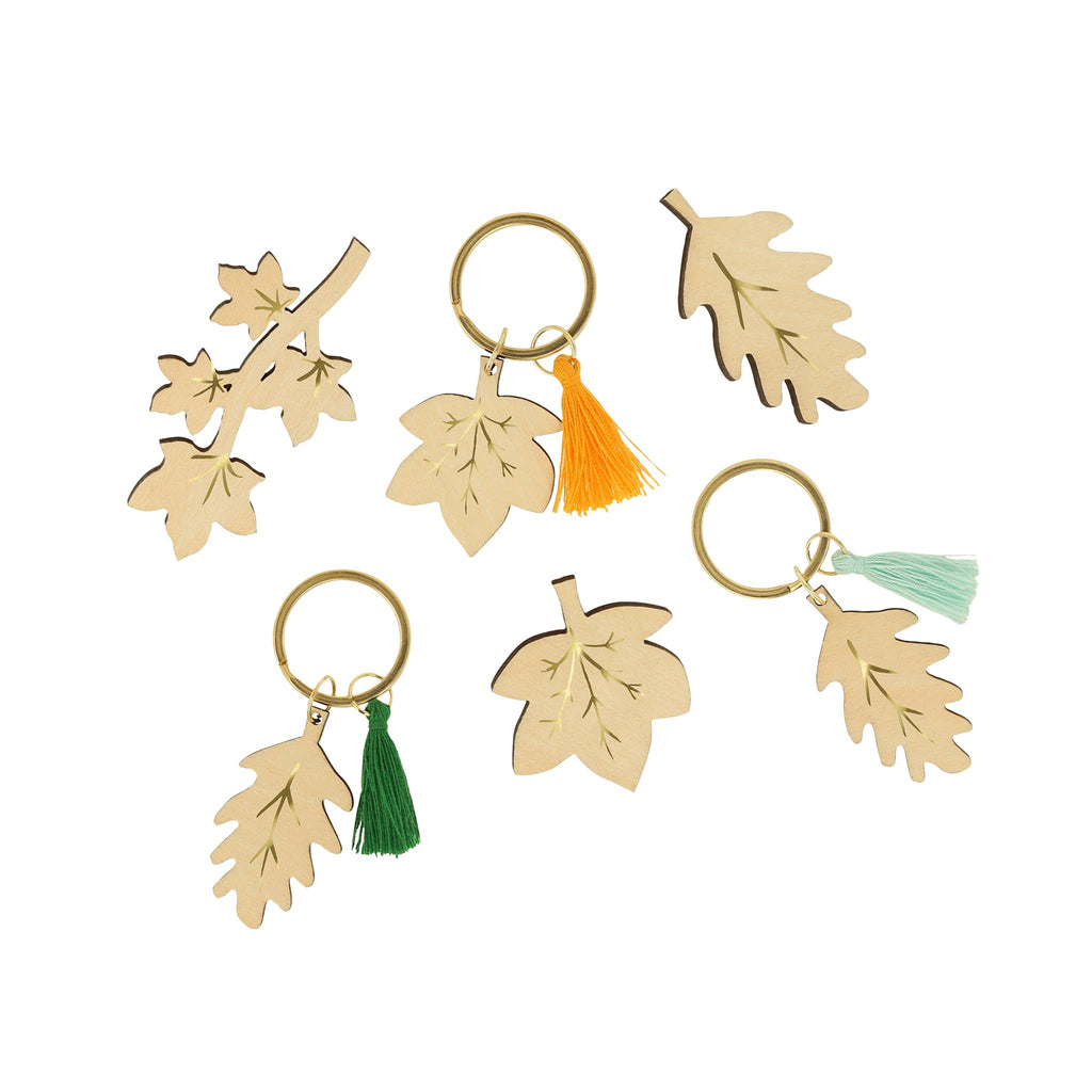 Set of wooden leaf-shaped brooches and keychains with colorful tassels on a white background.