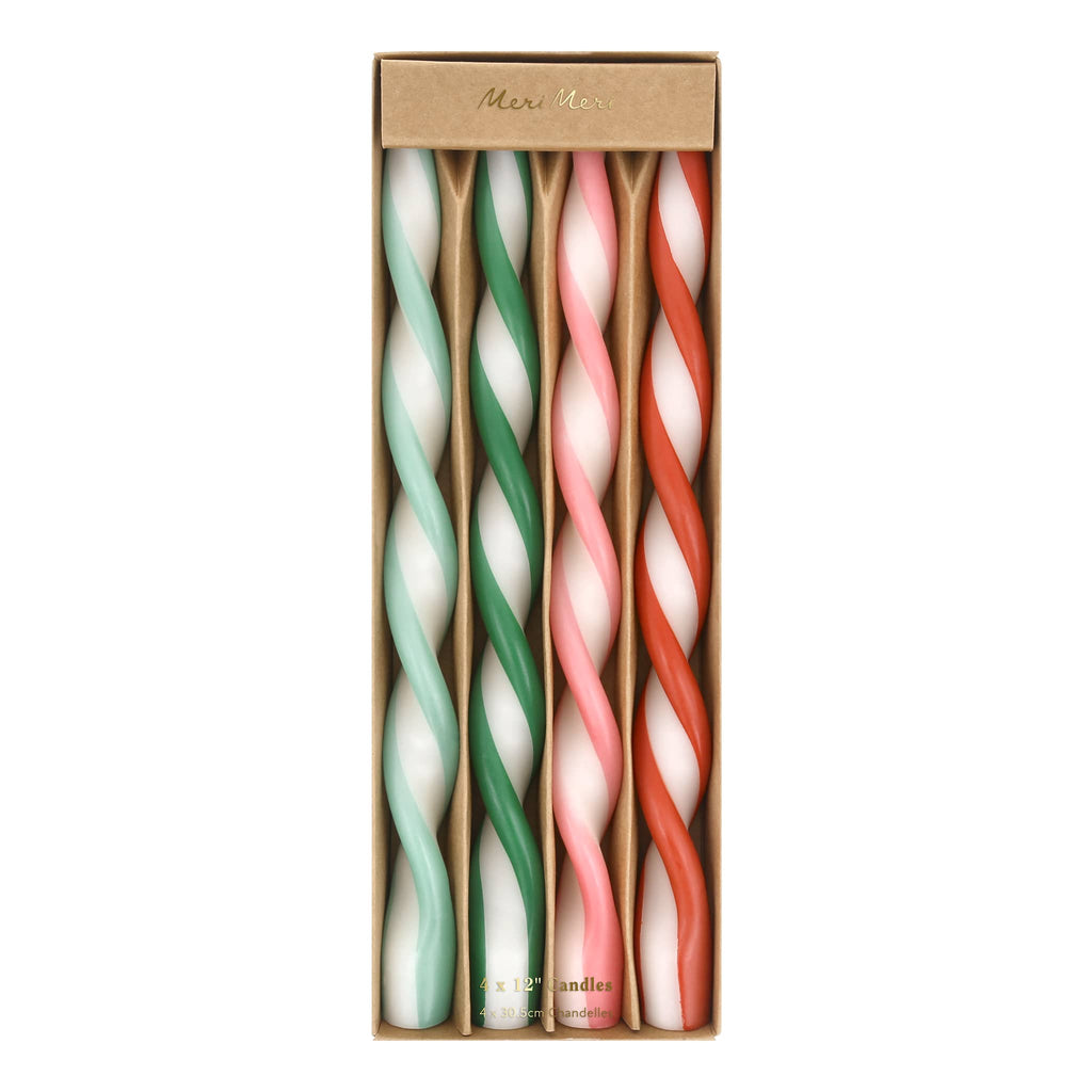 Set of four twisted candles in green, white, pink, and red in packaging on a white background.
