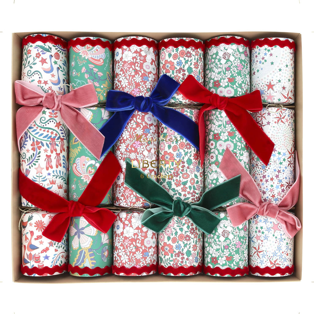 Decorative crackers with floral prints and colorful velvet bows in a box, on a white background.