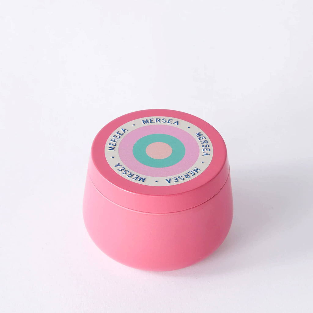 Mersea Cabana Flower scented 3 ounce soy blend candle in pink tin with lid.