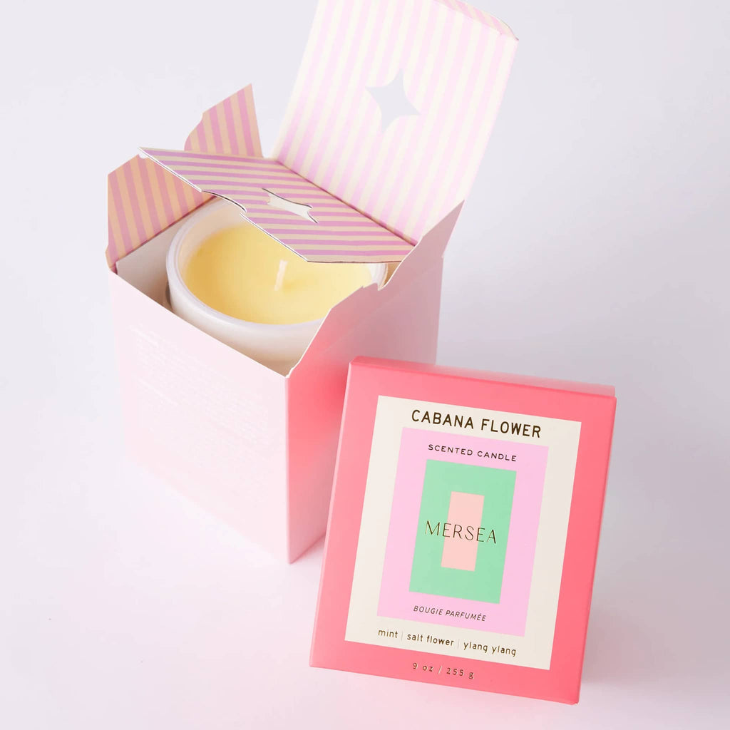 Mersea Cabana Flower scented 9 ounce soy blend candle in white glass vessel, inside and beside pink gift box.
