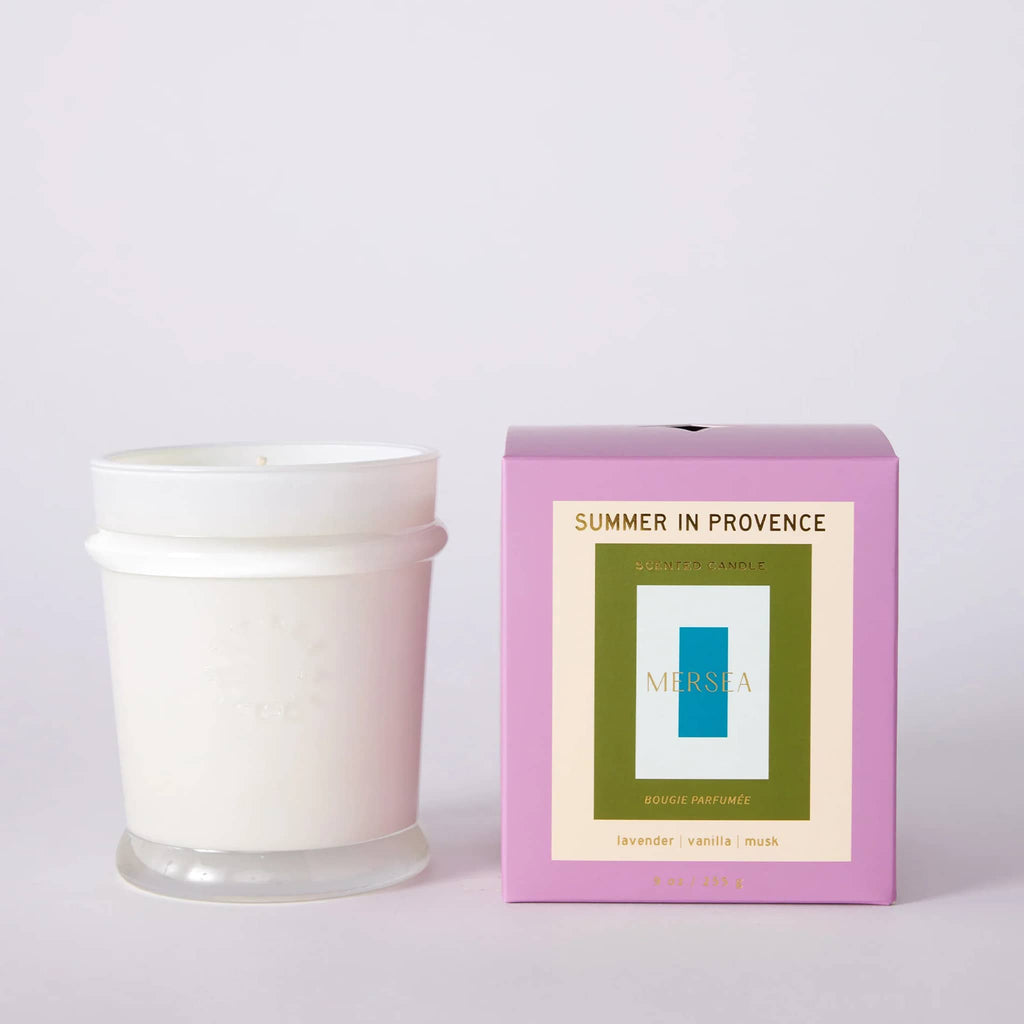 Mersea Summer in Provence scented 9 ounce soy blend candle in white glass vessel beside lilac gift box.