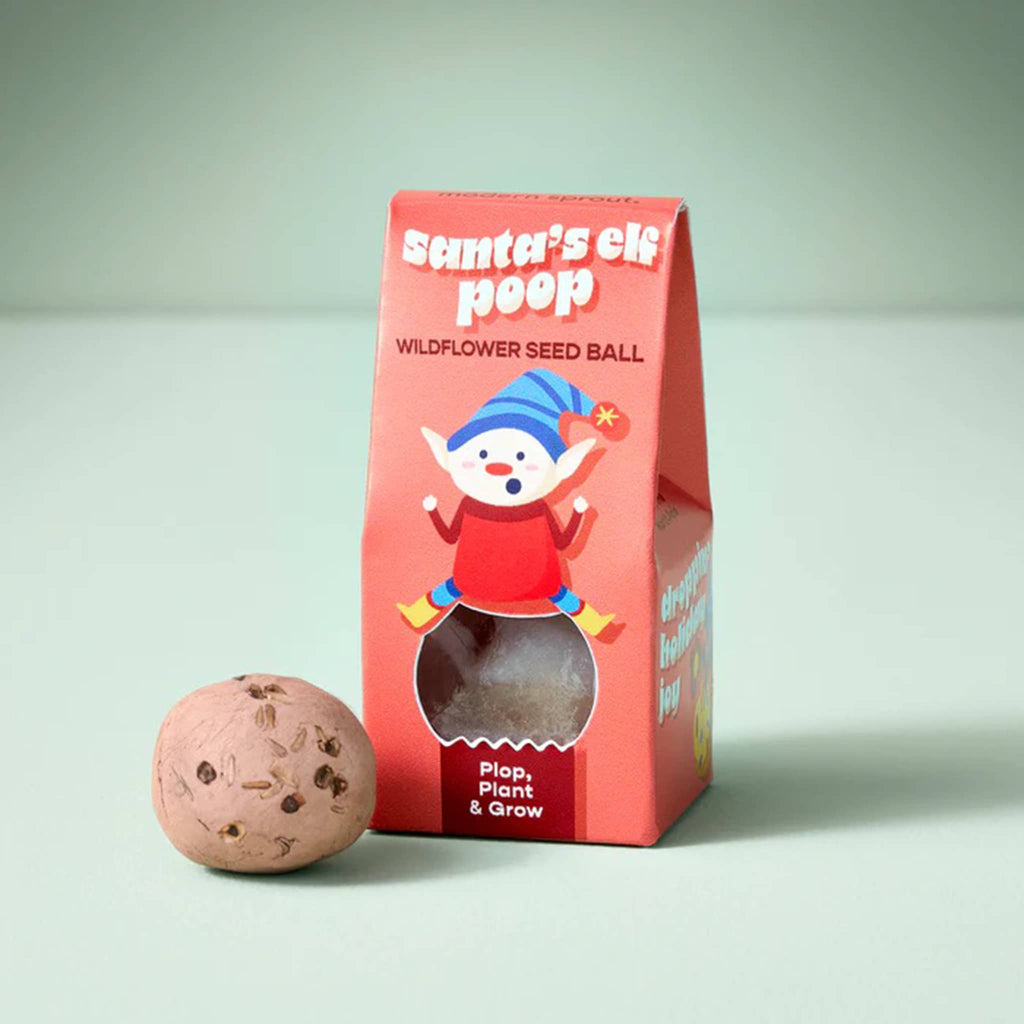 Red packaging of 'Santa's Elf Poop' wildflower seed ball with a tan seed ball on a light green background.