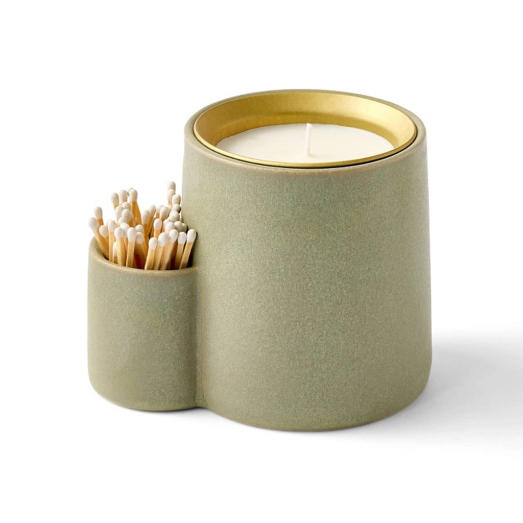 Green flecked ceramic candle holder with scented candle and white safety matches on a white background.