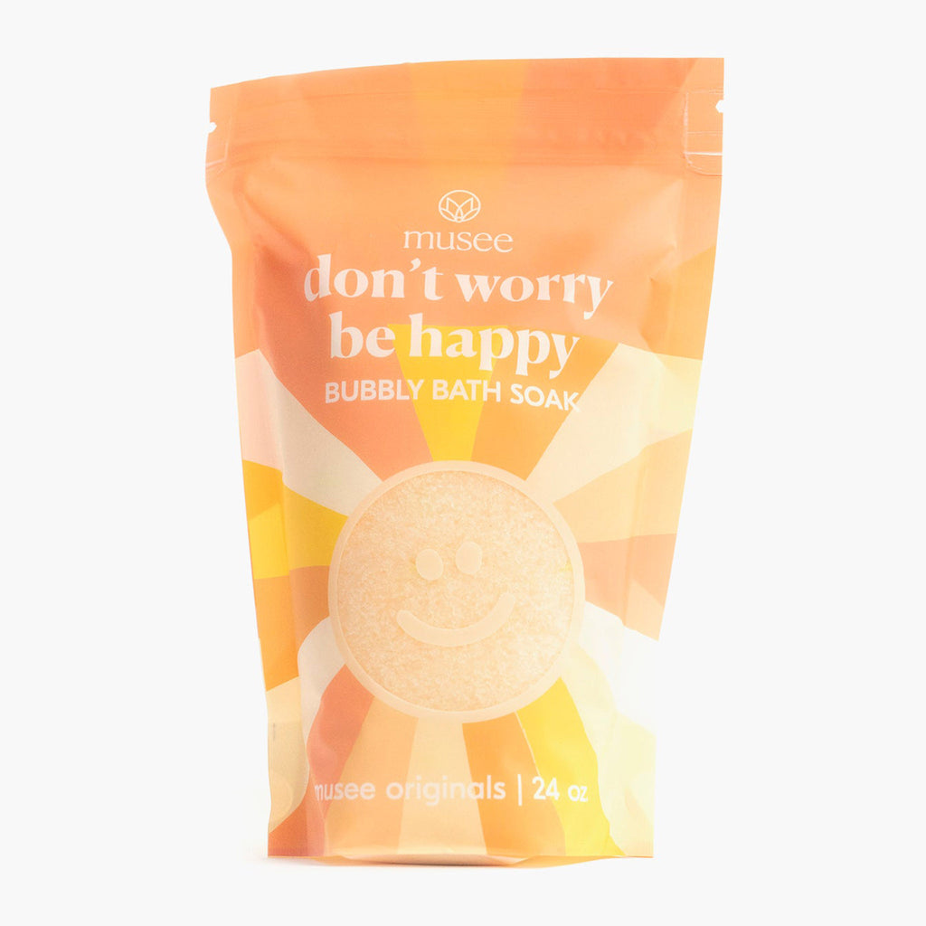 Musee Bath Don't Worry Be Happy bubbly bath soak in yellow and orange resealable bag with smiley sun illustration, front view.