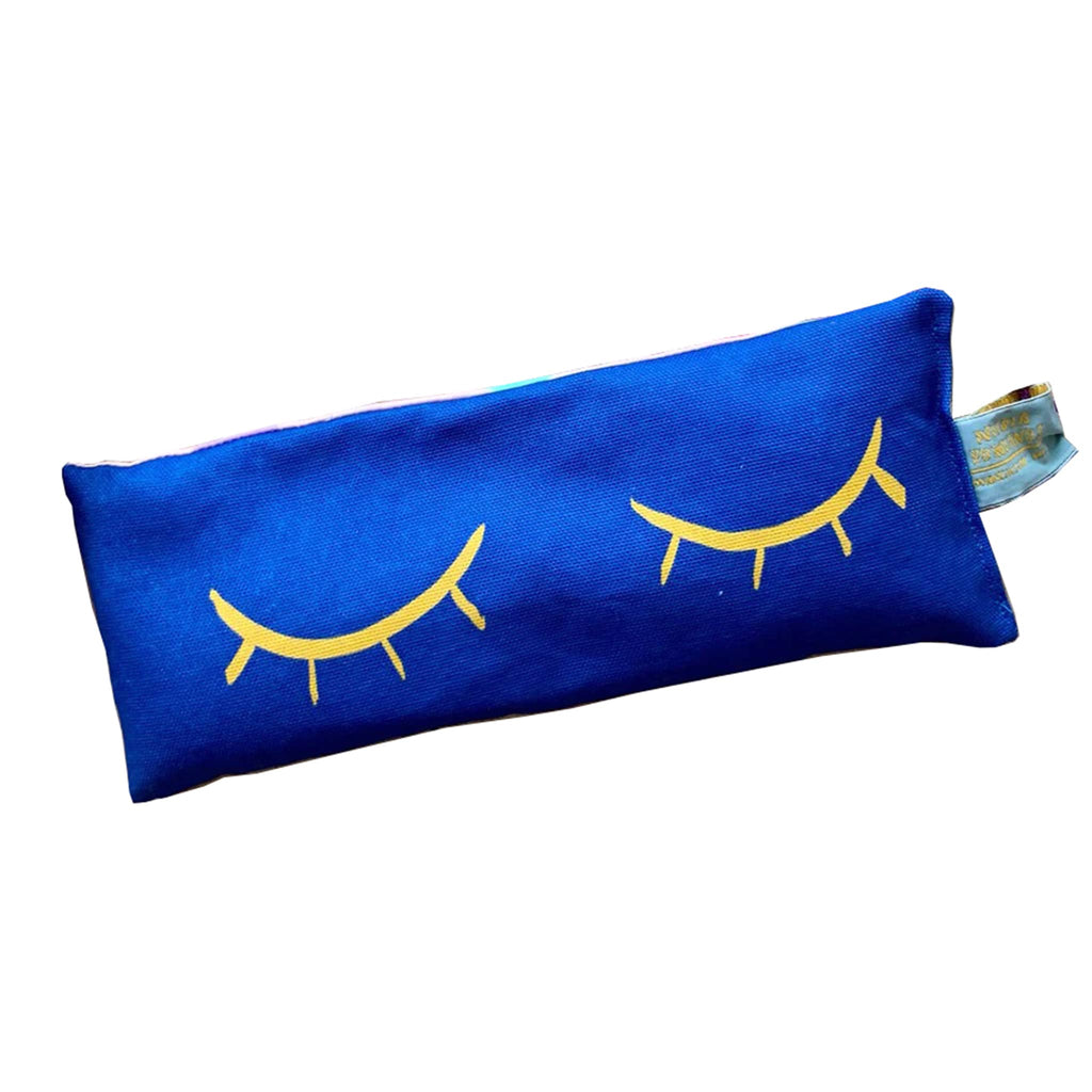 Nicola Rowlands Blue Eyes lavender scented weighted eye pillow with closed yellow eyes on a blue background.