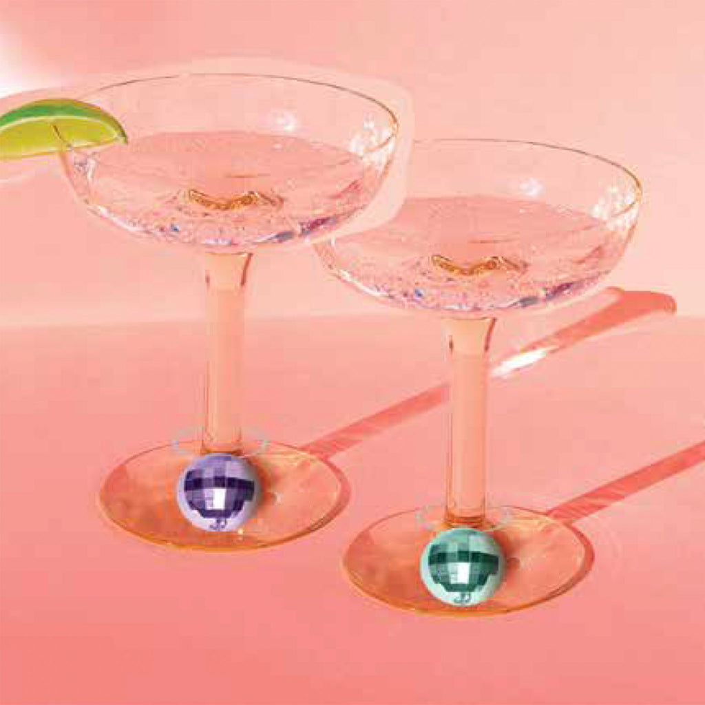NPW Disco Drink Charms in purple and green, each attached to a coupe glass on a coral background.