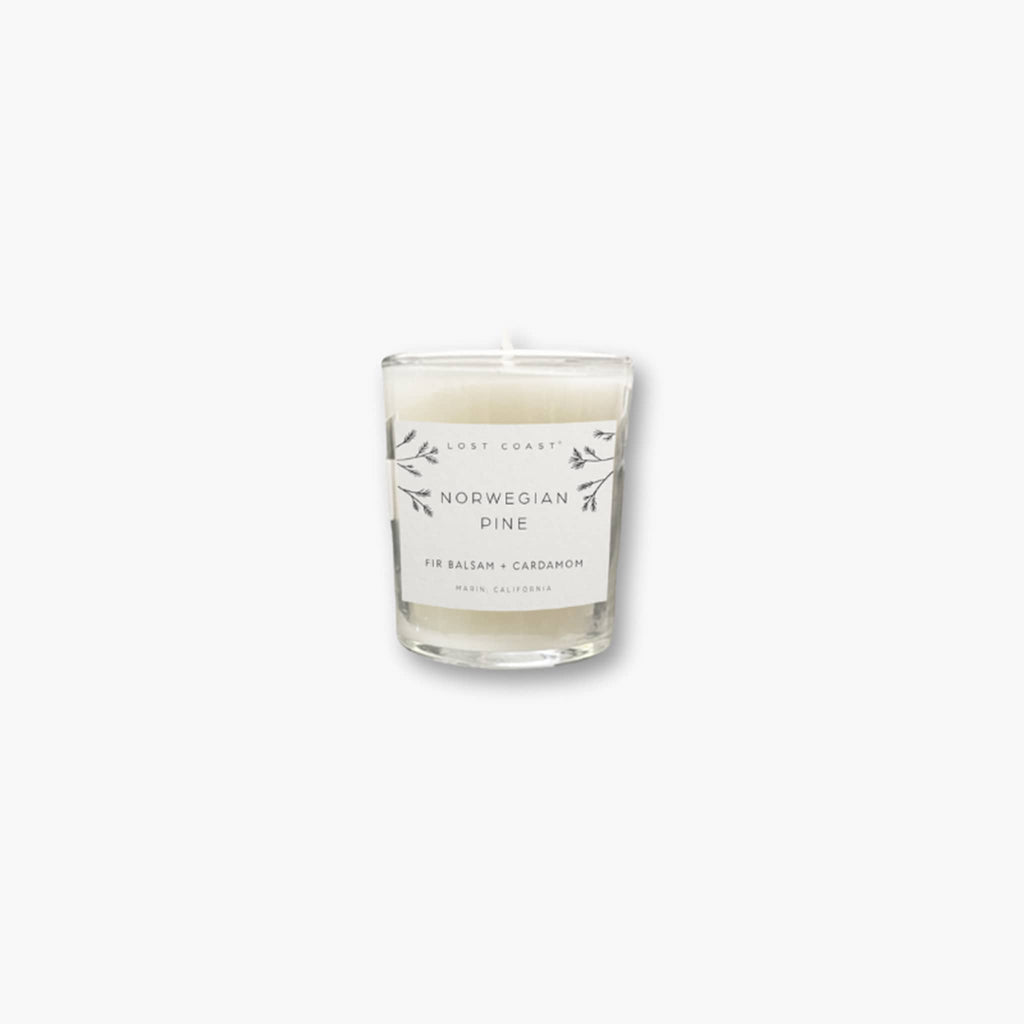 Lost Coast Norwegian Pine scented votive candle in clear glass vessel with white label on a white background.