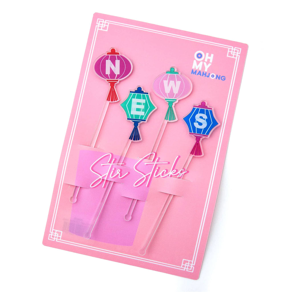Packaged stir sticks with mahjong winds lantern designs on a pink background.