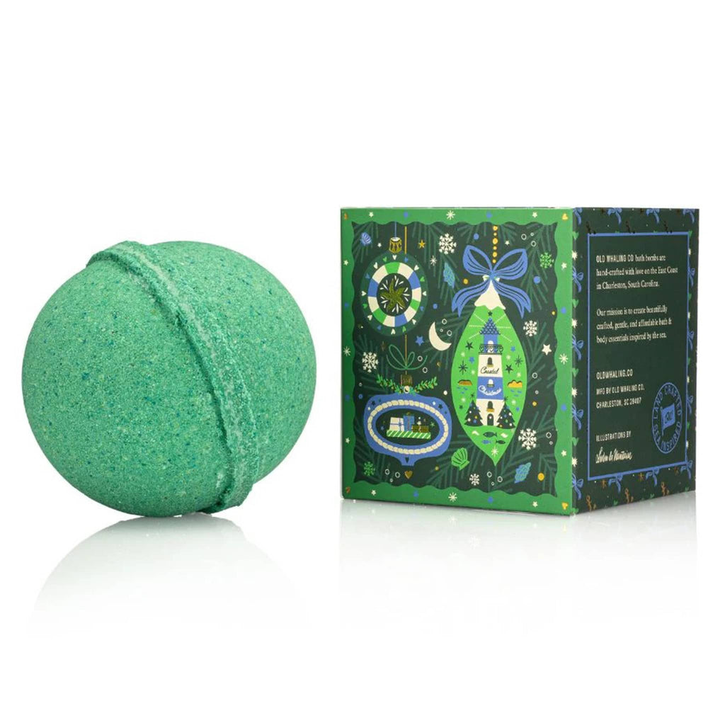 Green bath bomb next to its decorative packaging on a white background.