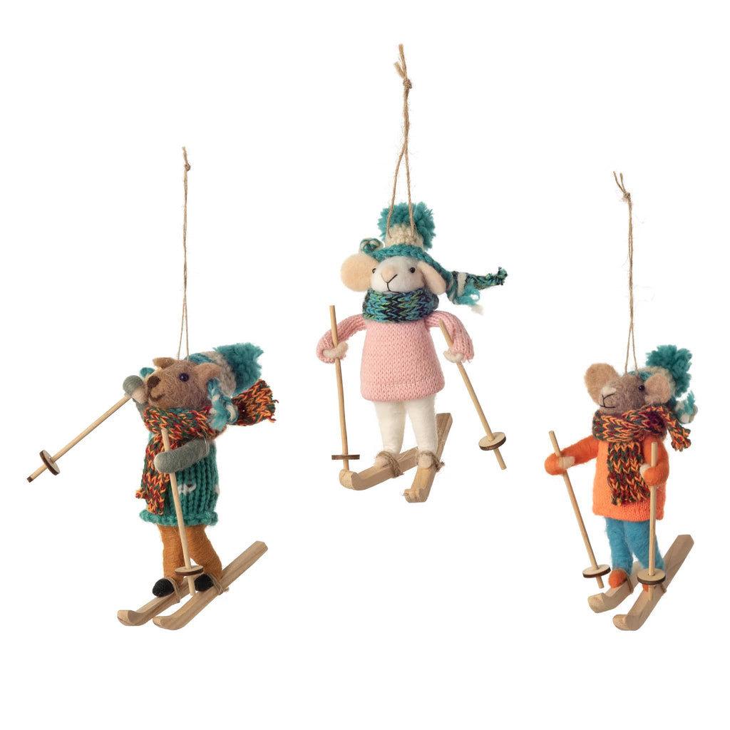 Three toy mice dressed in winter clothing and skis on a white background.