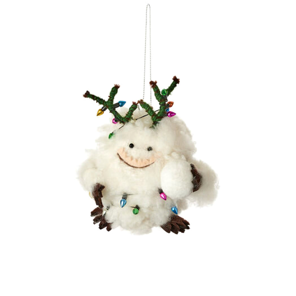 One Hundred 80 Degrees Abominable Snowman fluffy white holiday tree ornament with green branch antlers, brown arms and legs tangled up in colorful christmas lights.