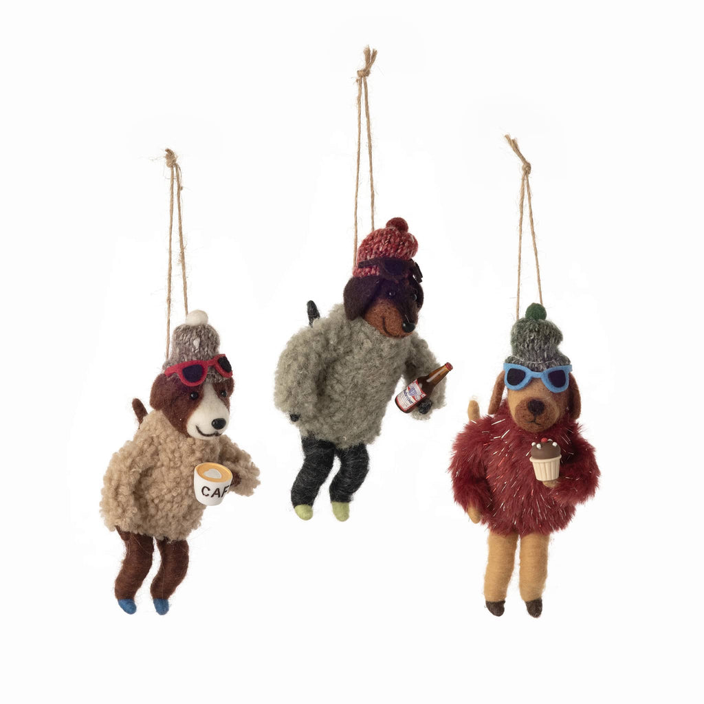Three dog ornaments in winter attire hanging on a white background.