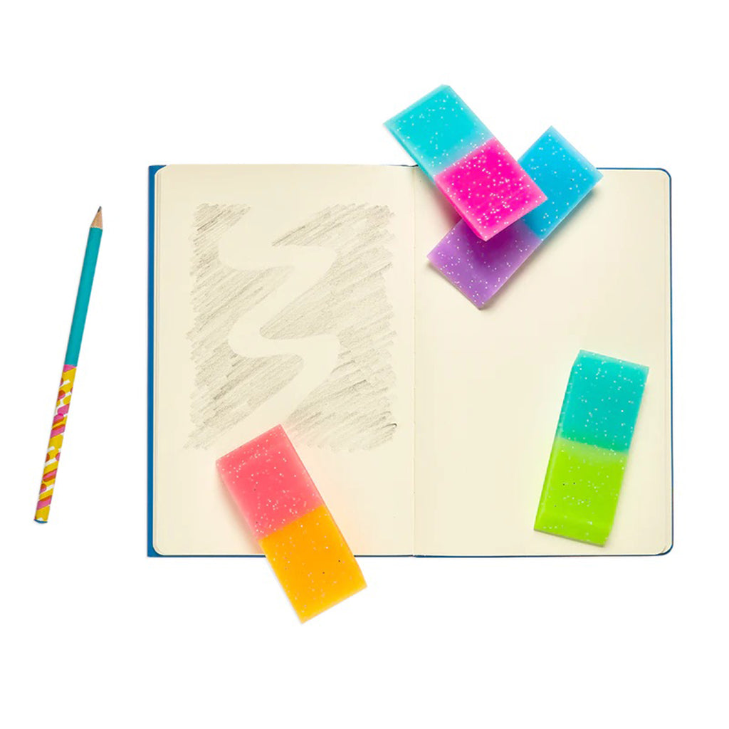 Ooly Oh My Glitter! Jumbo Pencil Erasers in 4 color combos with glitter, on a blank page notebook with pencil to show size.