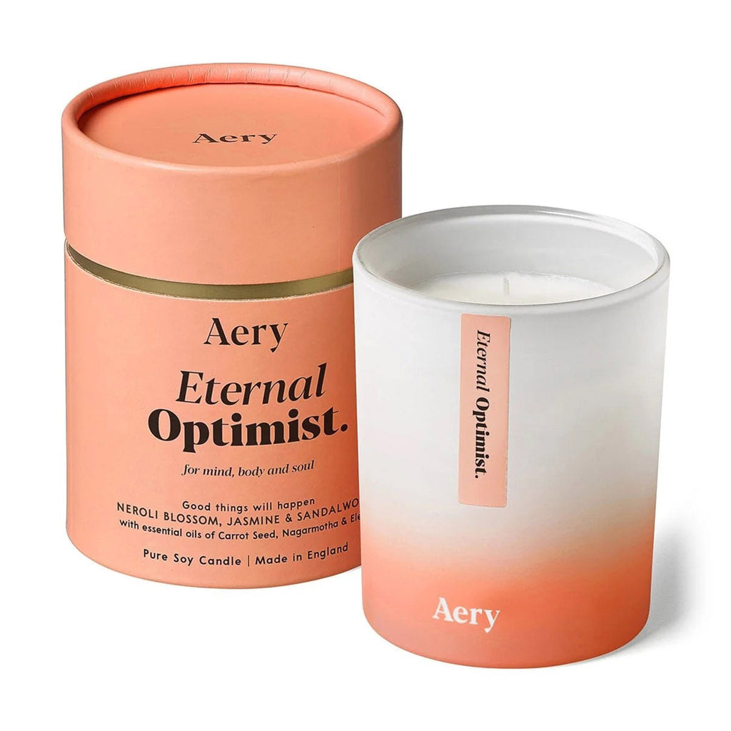 Osmology Aery Living Eternal Optimist Neroli Blossom, Jasmine and Sandalwood Scented Soy Wax Candle in white and orange ombre matte glass vessel with orange tube packaging.