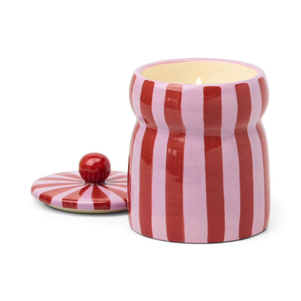 Pink Peppermint candle in ceramic jar with pink and red stripes, lid off and wick lit, on a white background.