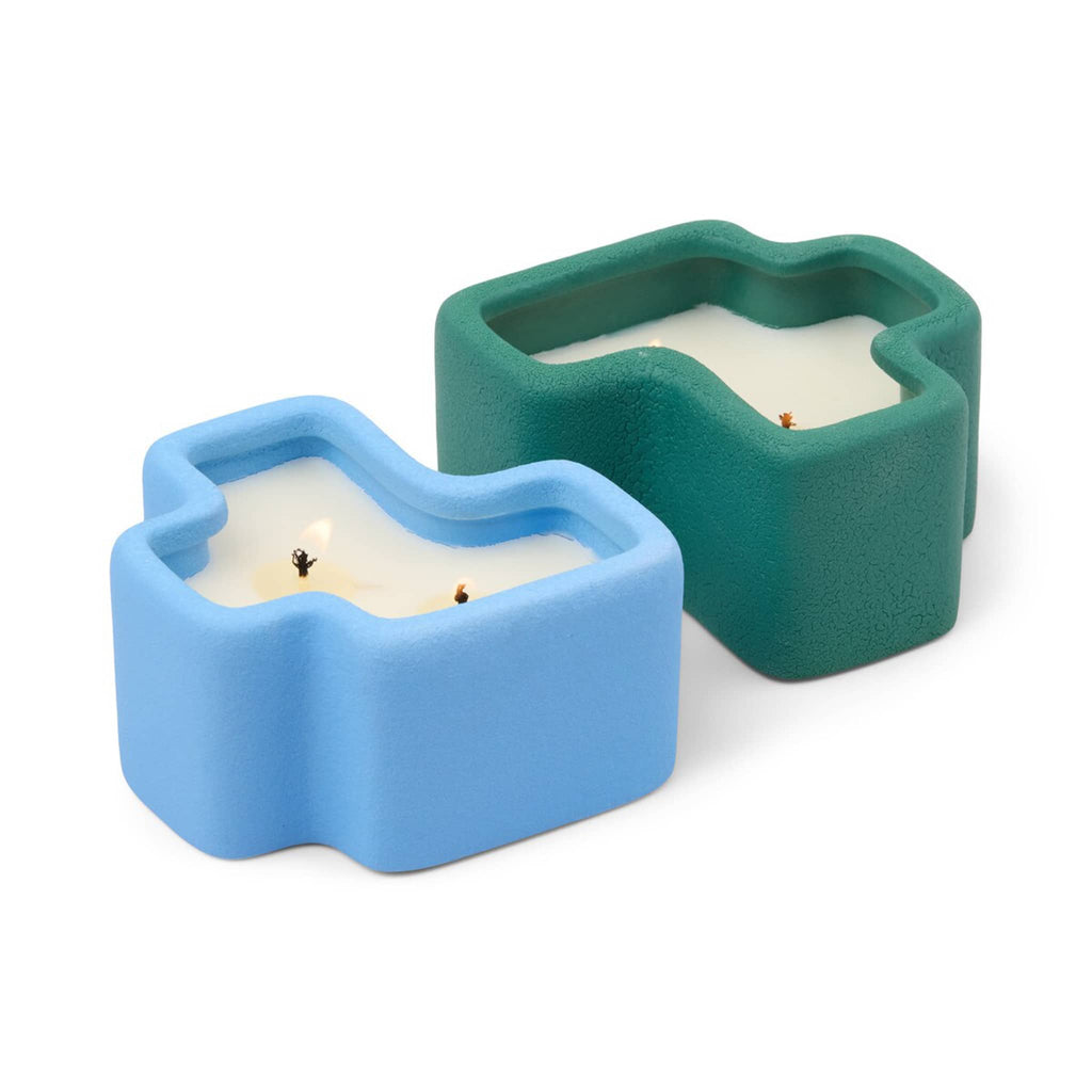 Two ceramic candle holders in blue and green shaped like puzzle pieces on a white background.