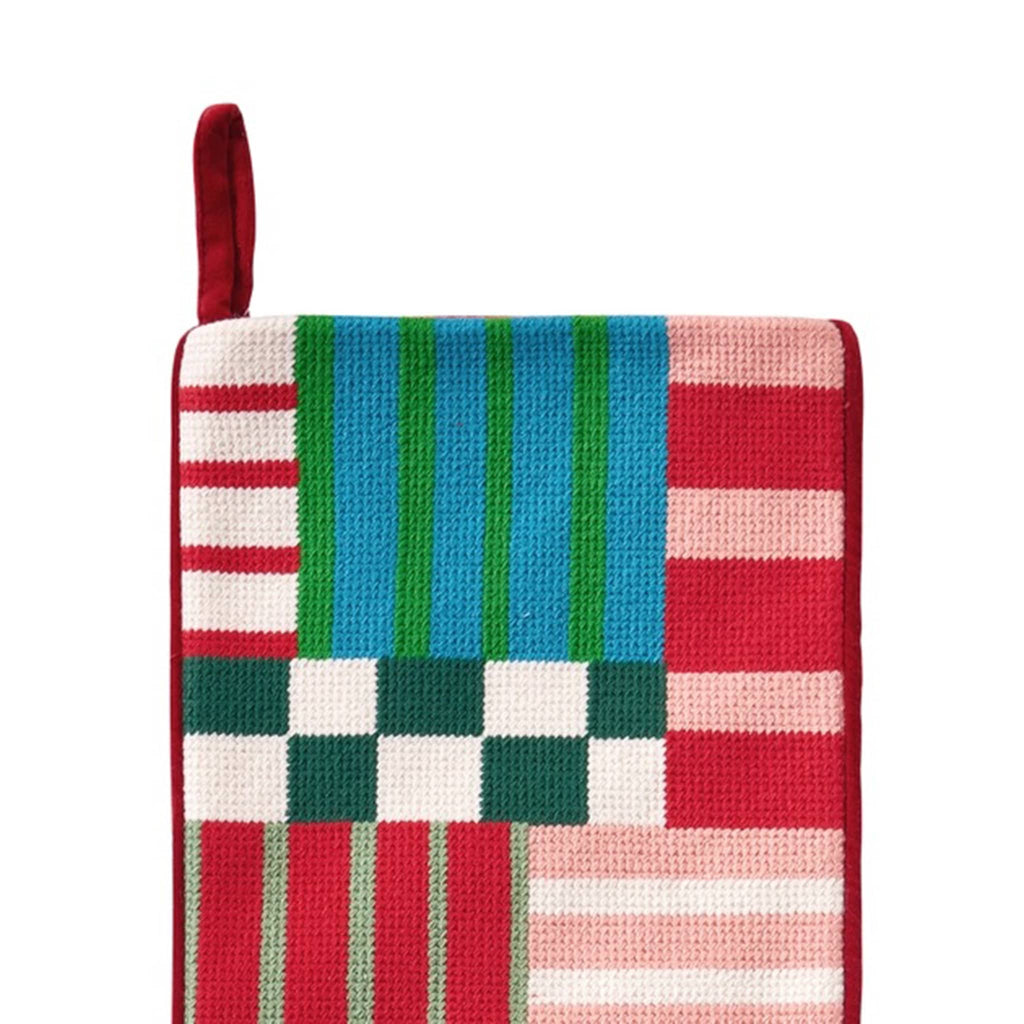 Detail of colorful patchwork needlepoint Christmas stocking on a white background.