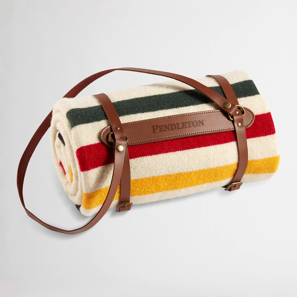 Pendleton Glacier National Park Throw Blanket in ivory, rolled up in leather carrier.