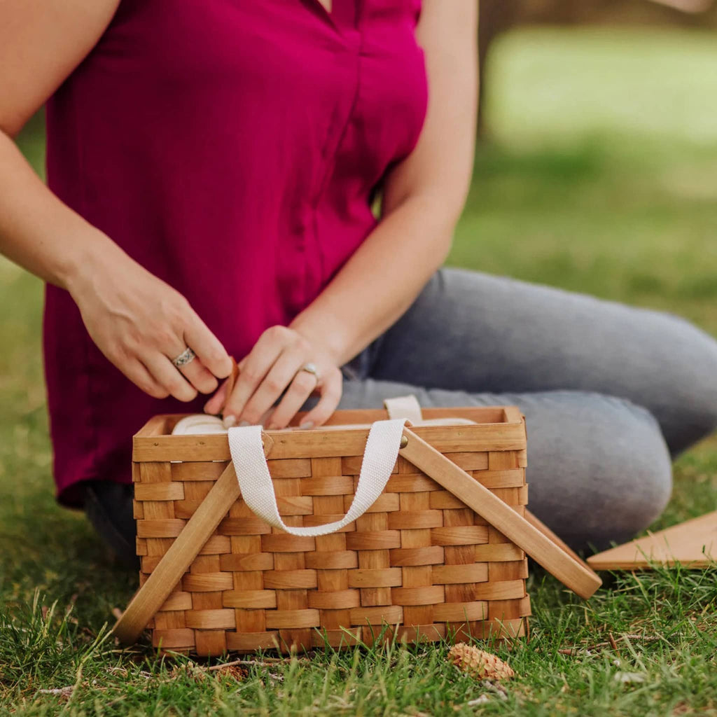 Picnic Time Poppy Personal Handwoven Wicker Picnic Basket, shown open and on grass with a person for scale.