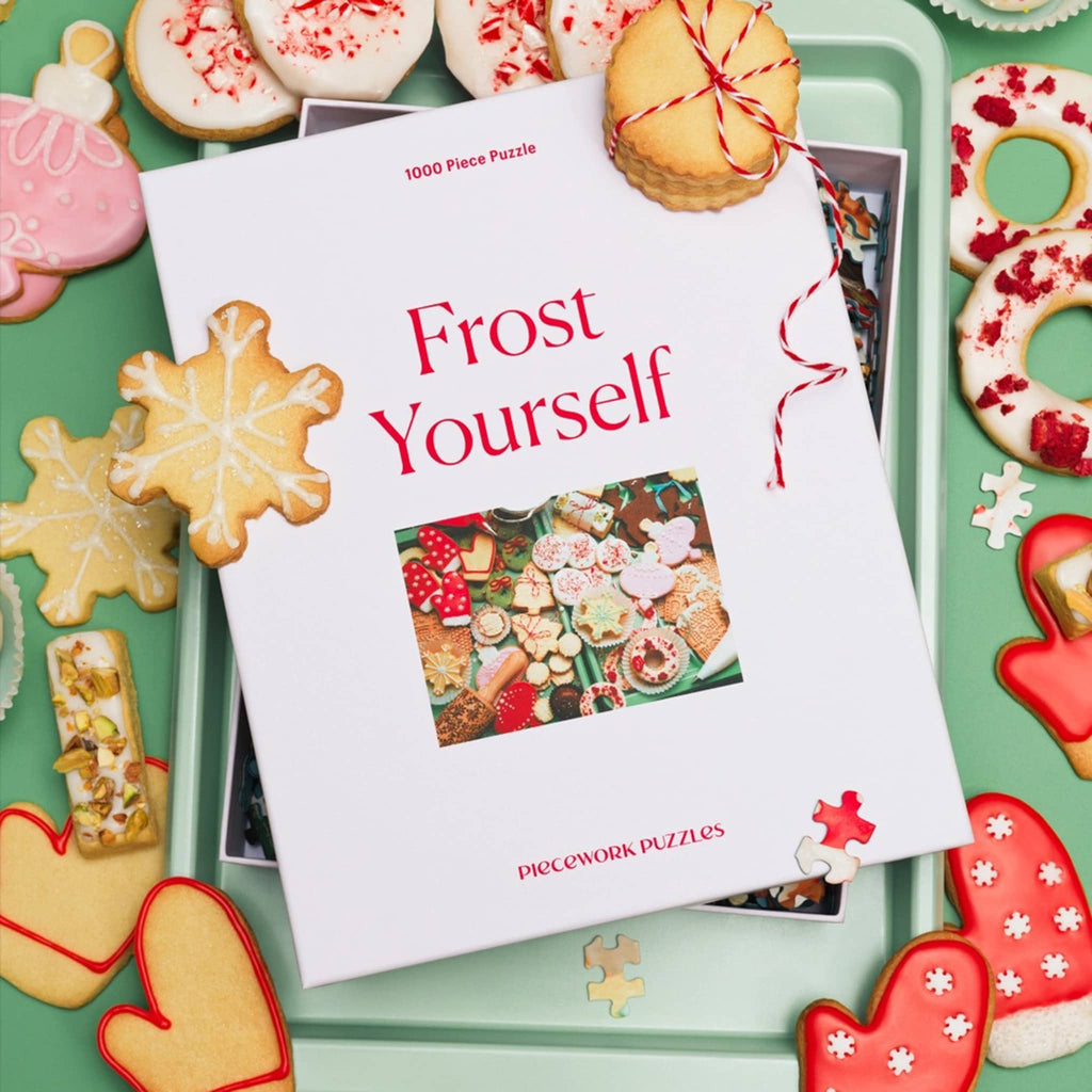 Frost Yourself puzzle in box surrounded by decorative cookies on a green tray.