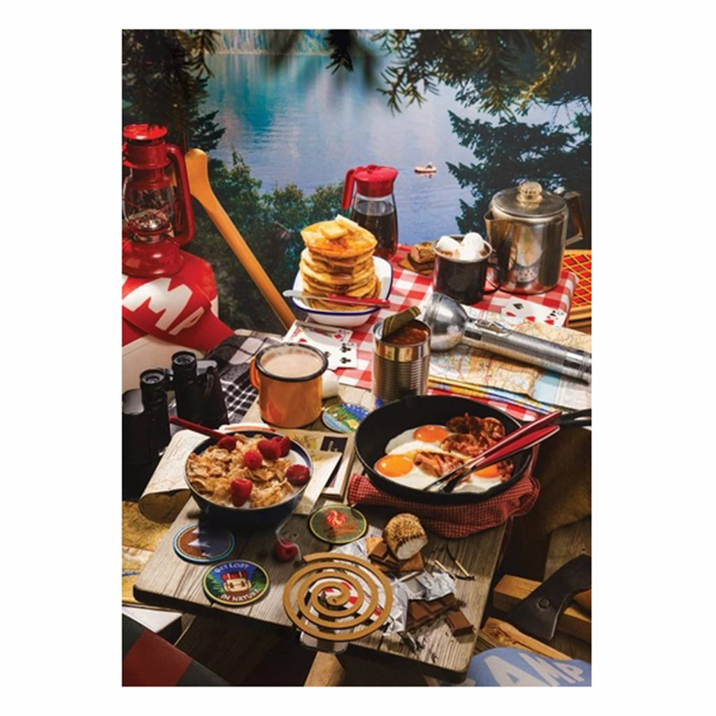 Camping table with breakfast food and outdoor gear by a lake.