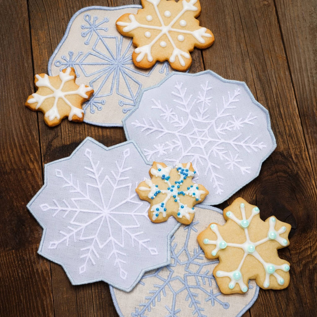 Snowflake-shaped linen napkins with cookies on a wooden surface.