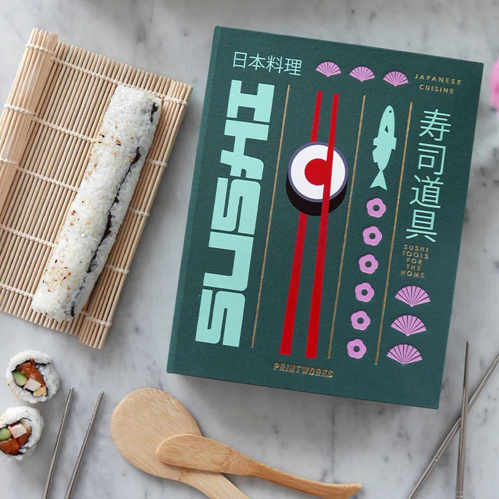 Printworks The Essentials Sushi Tools Kit in green book box packaging, on marble surface with sushi hand rolls beside.