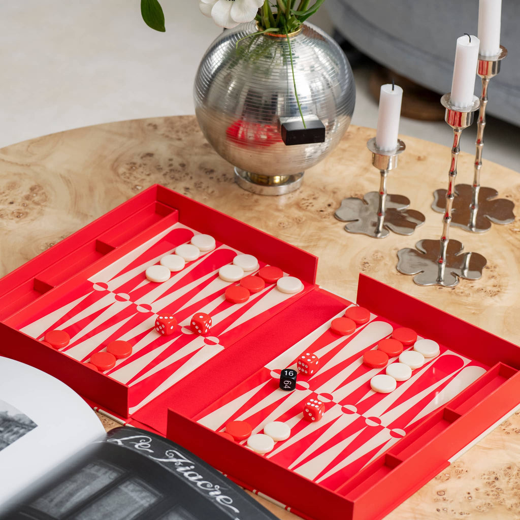 Backgammon set with red and white pieces on a wooden table.