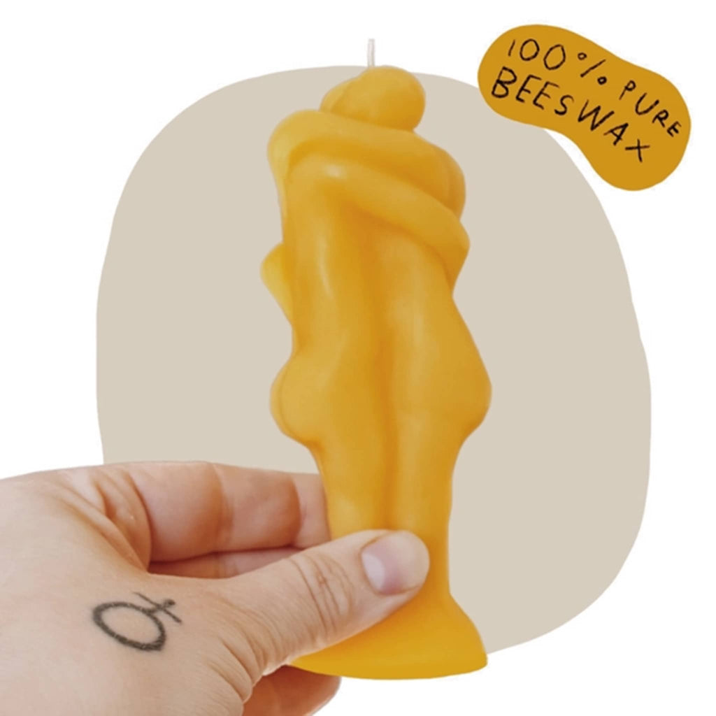 Rani Ban natural beeswax candle that looks like 2 people hugging, side view with hand holding for scale.