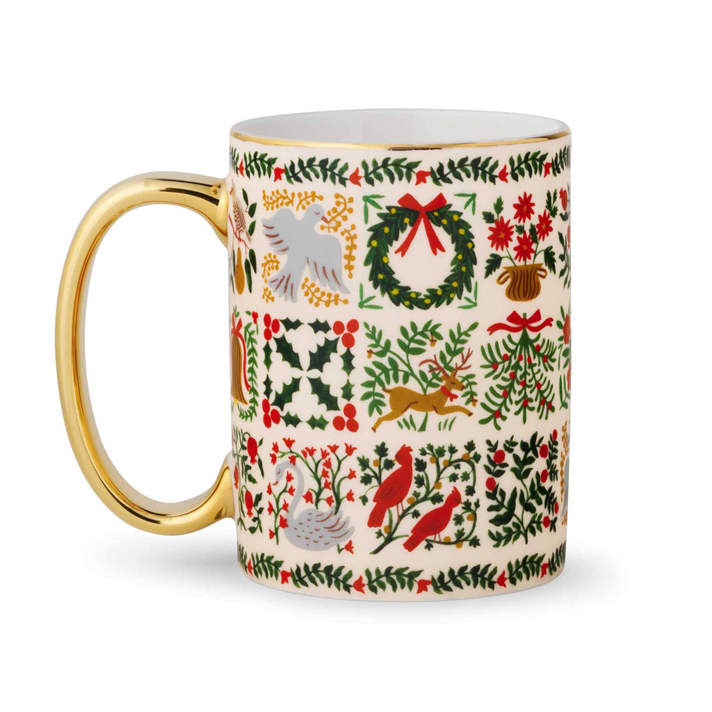 Rifle Paper Co. Christmastide porcelain holiday mug with gold rim and handle on left.