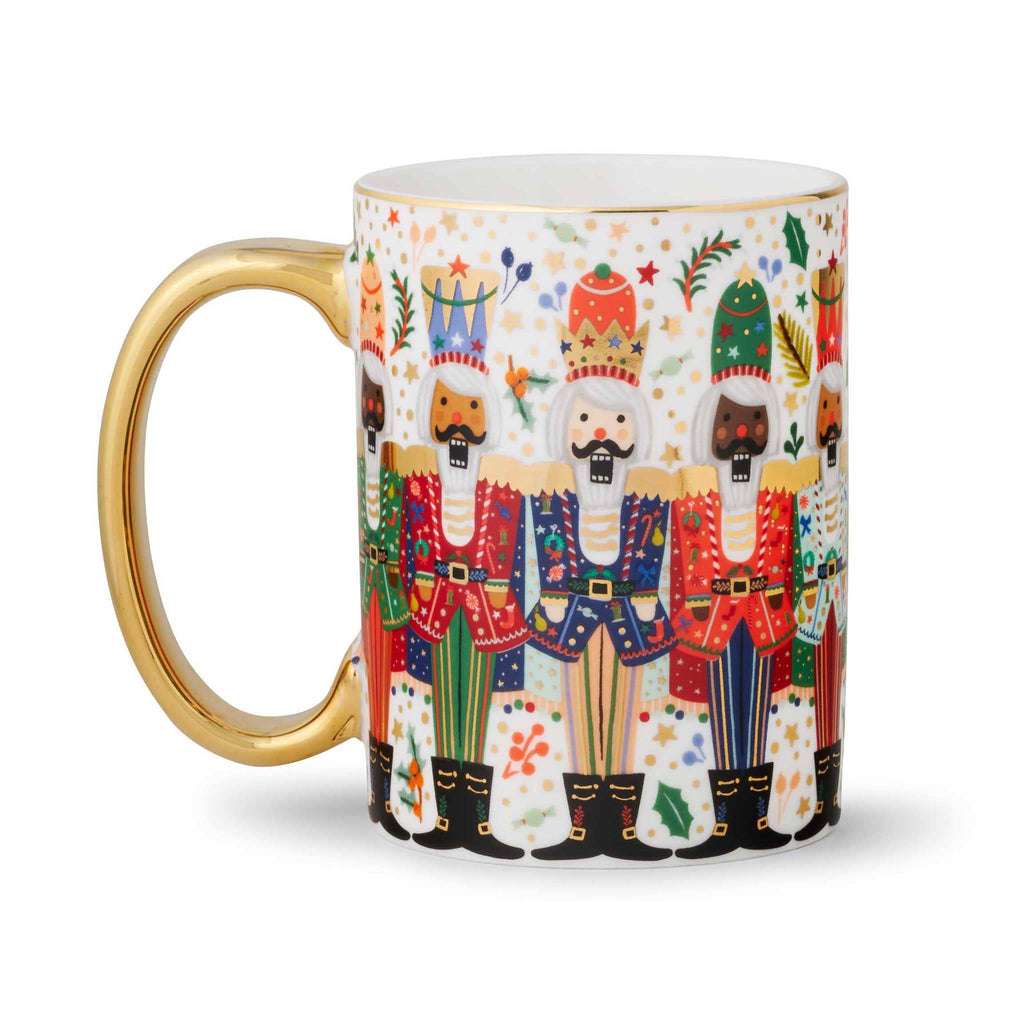 Rifle Paper Co. Nutcracker Brigade porcelain mug with gold rim and handle on the left.