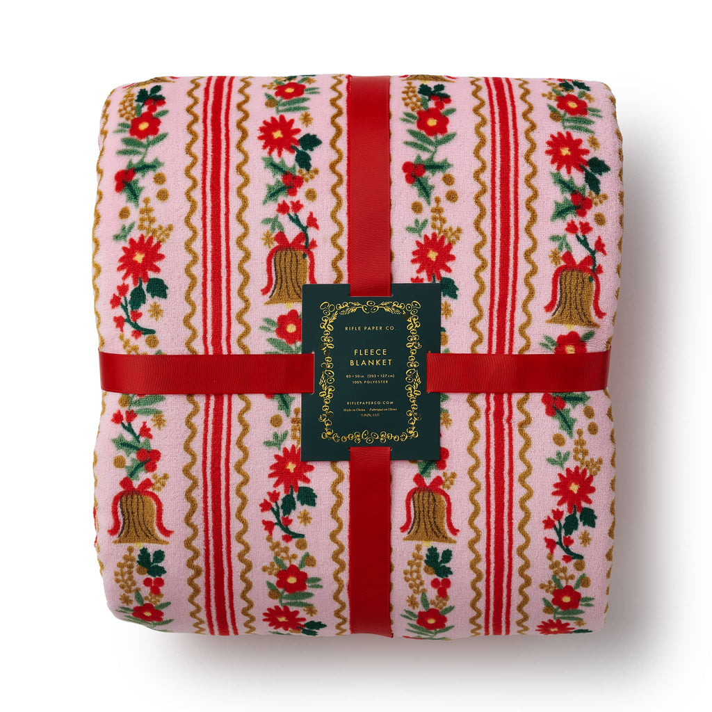 Folded fleece blanket with festive pattern and red ribbon on a white background.
