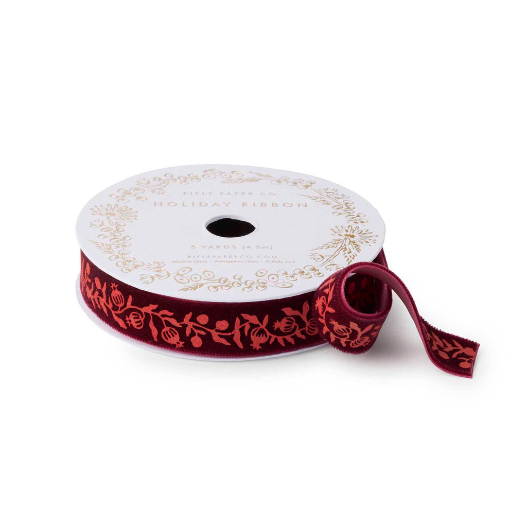 Rifle Paper Co. Christmastide pomegranate velvet ribbon on spool with the end curling out.