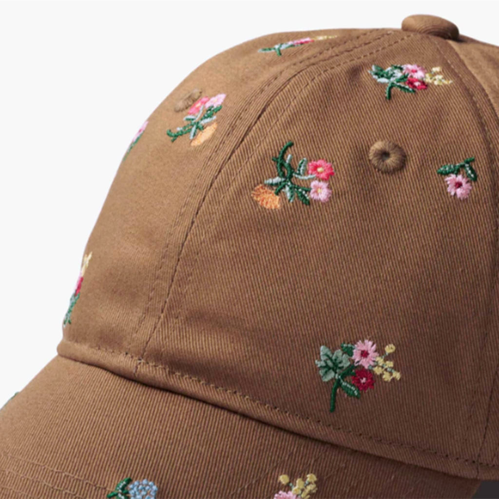 Brown cap with floral embroidery, detail, on a white background.